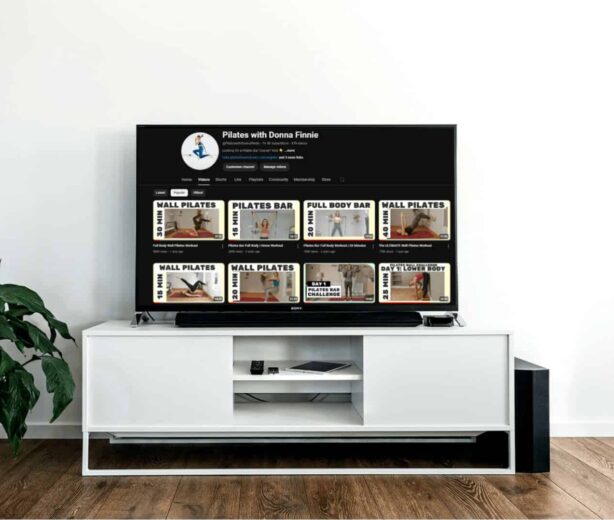 Pilates instructional videos on a TV screen in a modern studio setting.