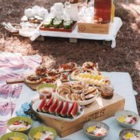 Fresh summer picnic with assorted desserts and drinks on a rustic outdoor table. Enjoy a variety of sweet treats, fresh fruit, and refreshing beverages at a sunny outdoor picnic.