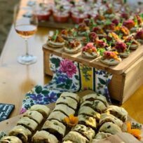 Elegant canapé platter with assorted finger foods and a glass of rosé wine. Perfect for social gatherings and stylish events. Delicious assorted canapés displayed on a wooden tray, ideal for parties and celebrations.
