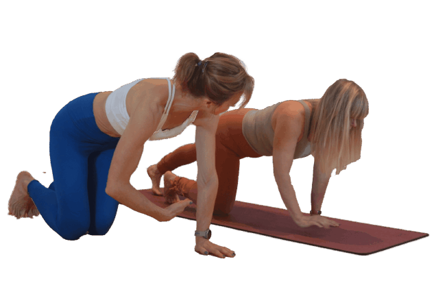 Pilates mat exercise with instructor guiding a client in a plank position for core strength.