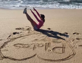 Woman performing Pilates on the beach with 